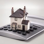 House resting on calculator concept for mortgage calculator, hom